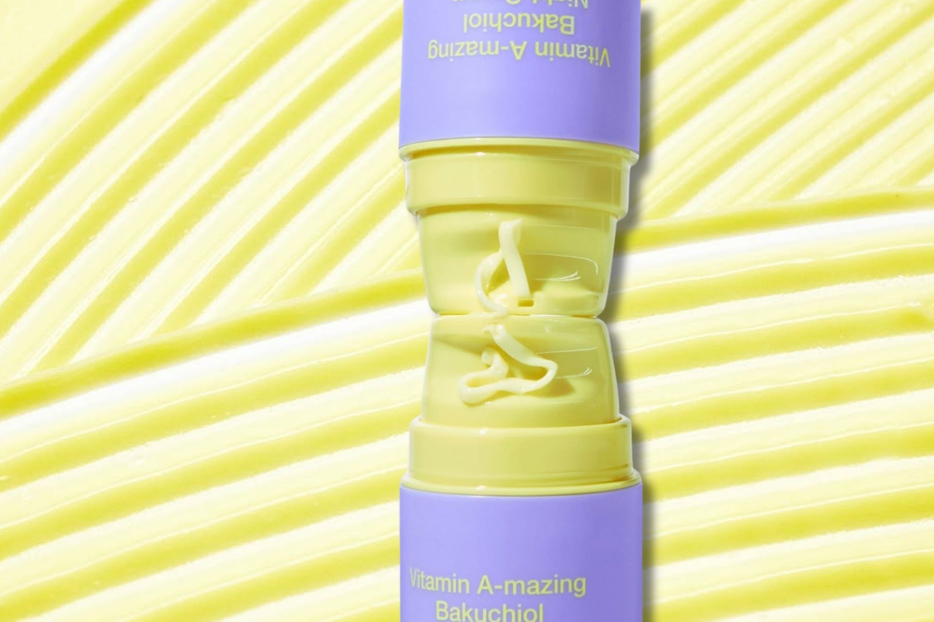 Wishtrend Vitamin A-mazing Bakuchiol retinol cream in yellow and lavender packaging with cream texture spread in the background.